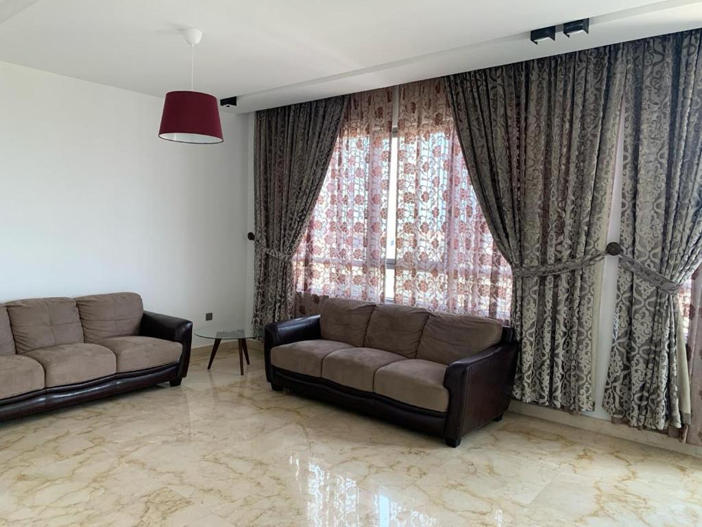 a living room with two couches and a large window at Saraya Al Olaya Tower family house in Al Khobar