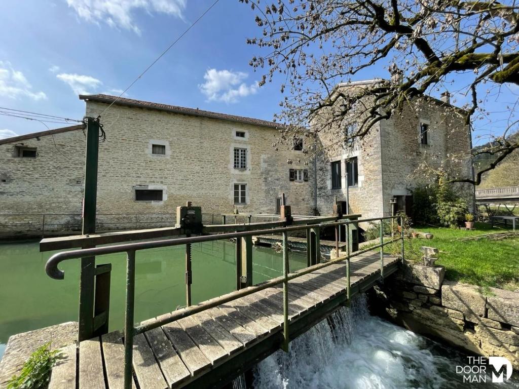uma ponte sobre um rio em frente a um edifício em Au moulin de Pascaline 