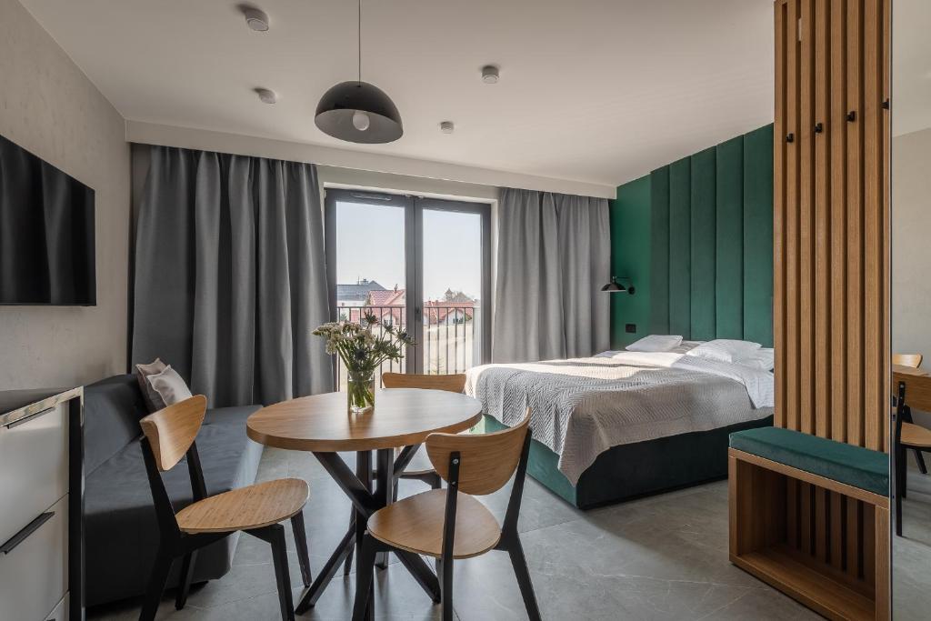 Habitación de hotel con cama, mesa y sillas en AVAPARTS apartament GREEEN, en Jastarnia