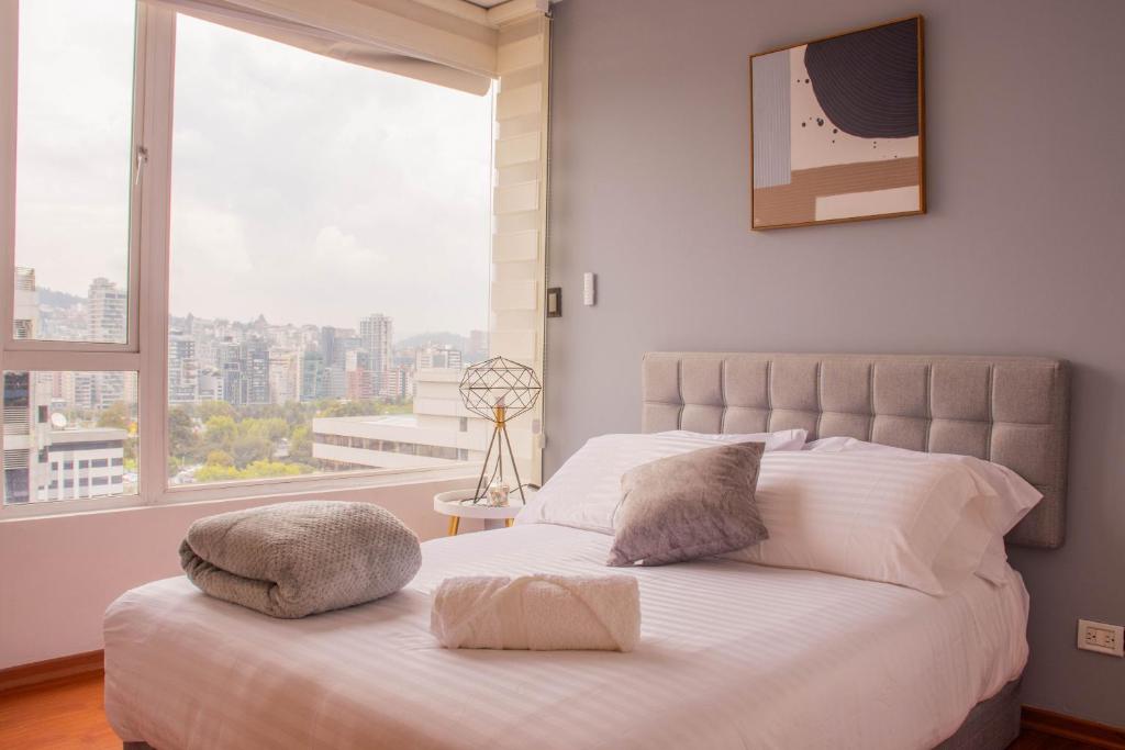 een slaapkamer met een wit bed en een groot raam bij 12 Floor Carolina Area best view 2br CCI Quito Coliving Ecuador in Quito