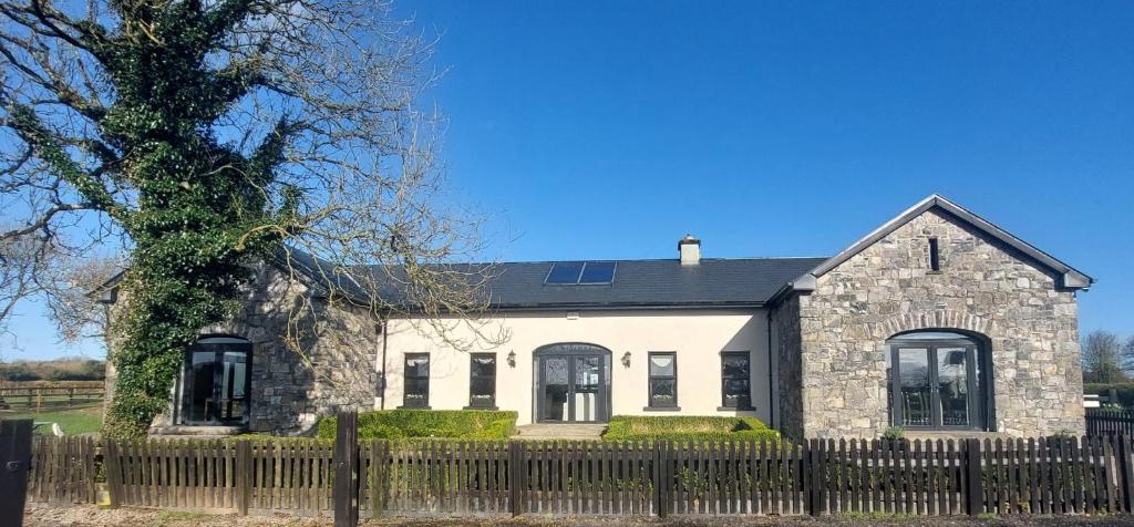 uma casa de pedra com uma cerca e uma árvore em Private Suites in the Burren em Corrofin