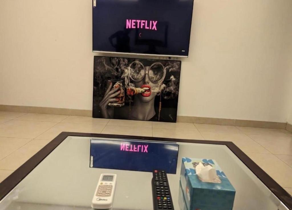 a tv and remote controls on a glass table at British Hotel - Johar Town LHR in Lahore