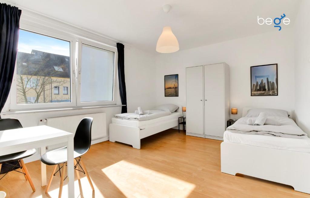 1 dormitorio con 2 camas, escritorio y ventana en BEGE APARTMENTS WorkAway Residence, en Bochum