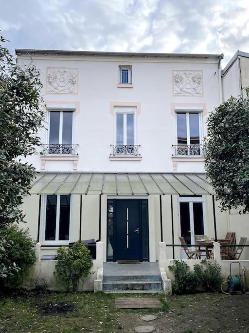 une maison blanche avec une porte et des fenêtres bleues dans l'établissement Maison familiale, idéale JO 2024, à Colombes