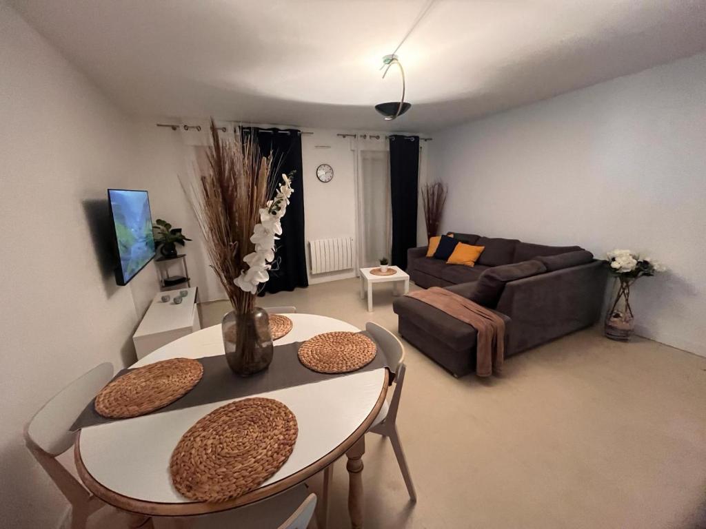 uma sala de estar com uma mesa e um sofá em Le Spacieux- Proche de Paris et Orly - Beau F2 de 52m2 en centre ville em Chilly-Mazarin