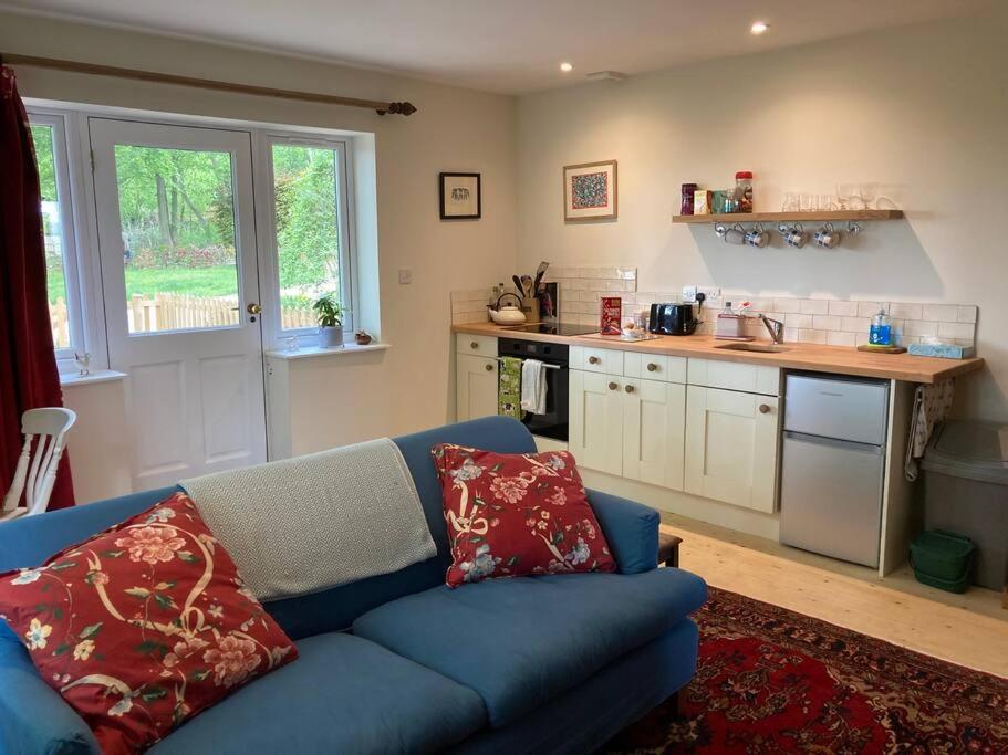 a living room with a blue couch and a kitchen at Cosy retreat in the heart of the Cotswolds. in Chipping Norton