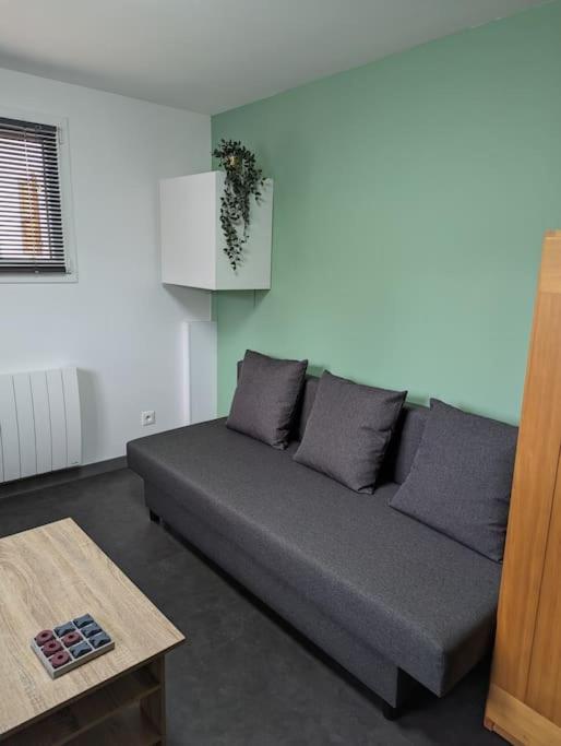 a gray couch in a living room with a table at La Madeleine d&#39;Eybens (Grenoble) in Eybens