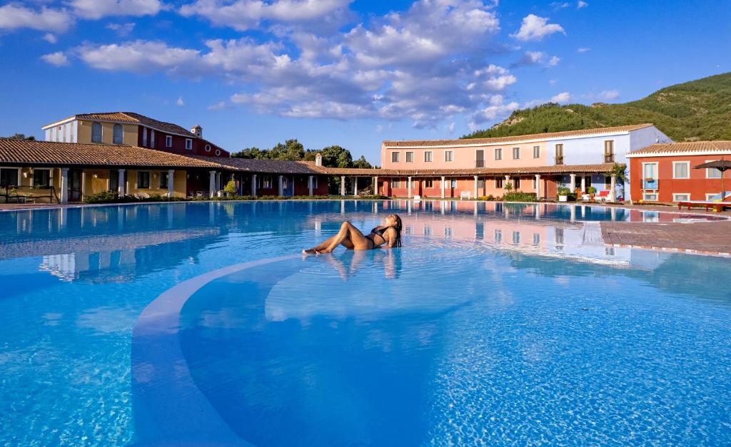 une femme qui se couche au milieu d'une piscine dans l'établissement ECO HOTEL ORLANDO Sardegna, à Villagrande Strisaili