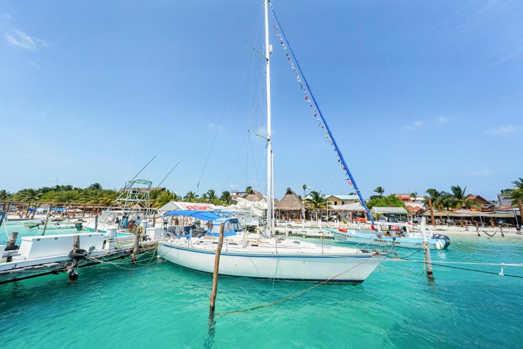 a sail boat docked at a dock in the water at Walk barefoot to beach! Private Sailboat at North End, queen bed, en-suite bath, AC in Isla Mujeres