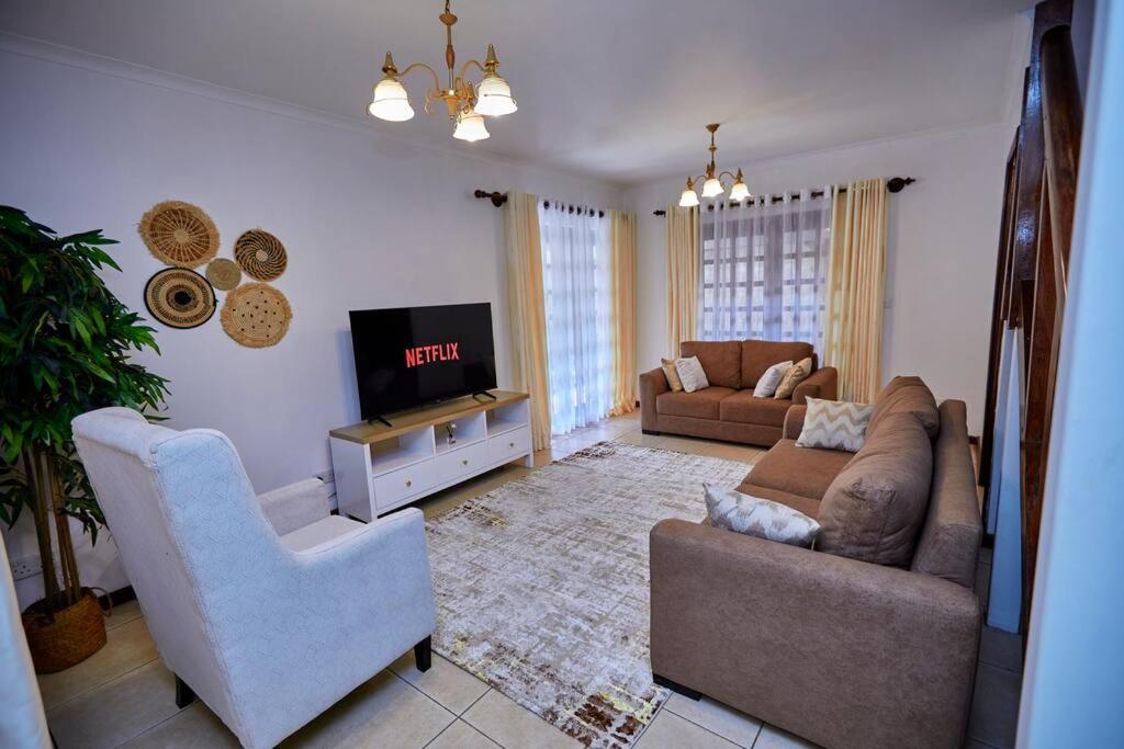 uma sala de estar com um sofá e uma televisão em Peaceful and Cozy Home in Arusha em Ngateu