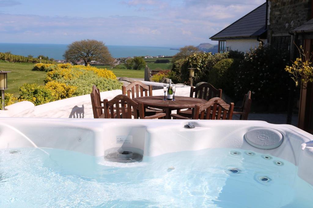 a hot tub in a yard with a table at Penlan Coastal Cottages in Aberporth