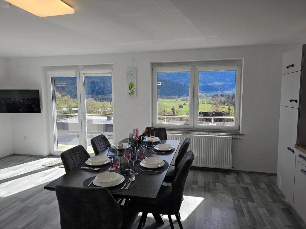 a dining room with a table and chairs and two windows at Appartment Jasmin in Liezen