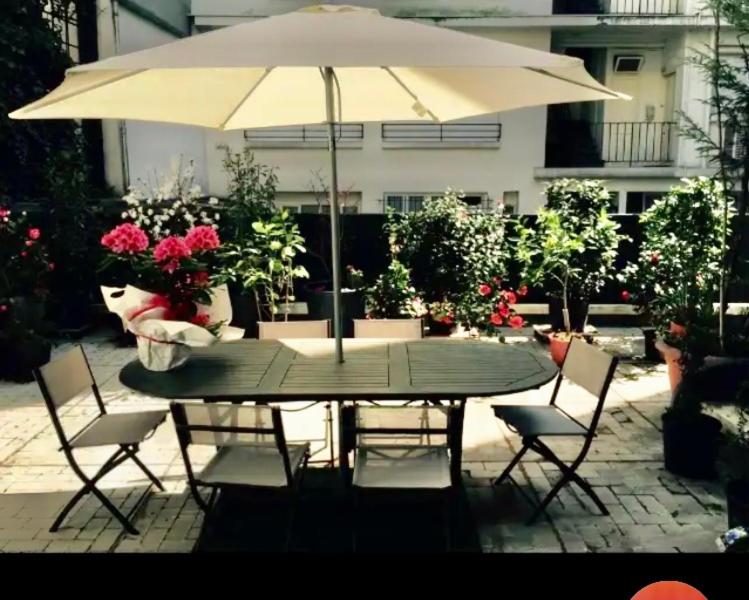 une table et des chaises avec un parasol et des fleurs dans l'établissement Tour Eiffel - Grand deux pièces avec terrasse, à Paris