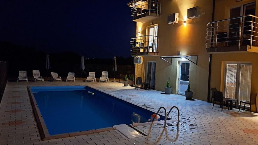 a swimming pool in front of a building at night at Prenociste jezerske zvezde in Veliko Gradište