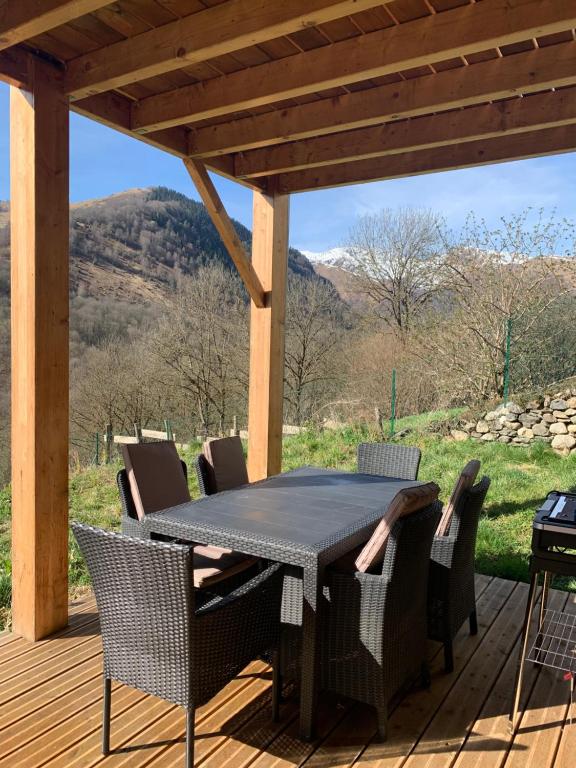 a table and chairs on a deck with mountains in the background at CHALET en RDJ en VALLEE de LUCHON in Castillon-de-Larboust
