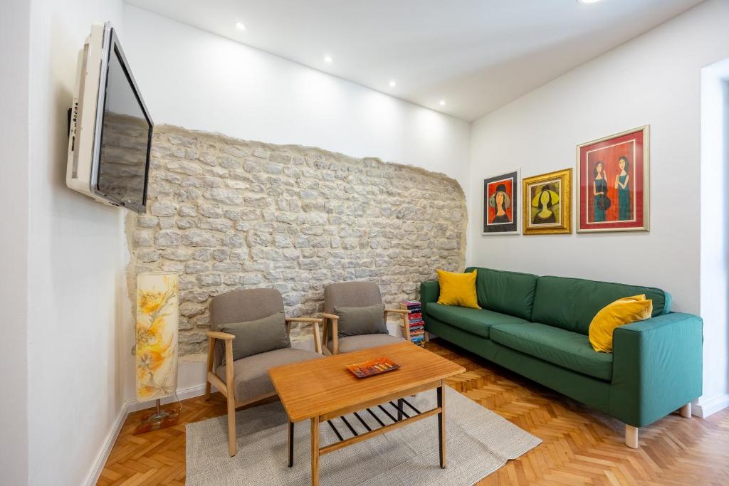 ein Wohnzimmer mit einem grünen Sofa und einem Fernseher in der Unterkunft Zadar Center Apartment in Zadar