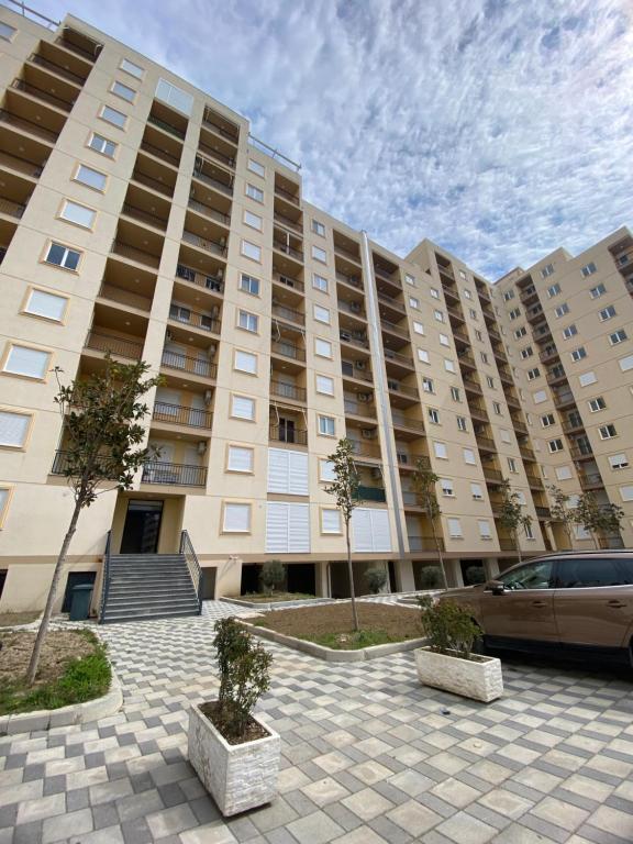 ein großes Gebäude mit einem davor geparkten Auto in der Unterkunft Your beach house holidays with all utilities in Shëngjin