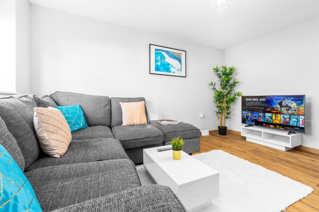 a living room with a gray couch and a tv at Modern 2 Bedroom Apartment - Off-street Parking - Top Rated - 1aS 