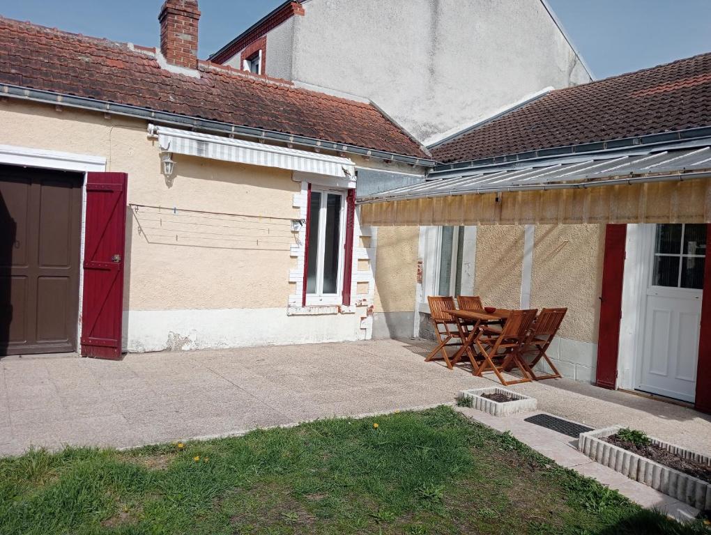 a patio with a table and chairs next to a house at Maison EL Marielle in Vierzon