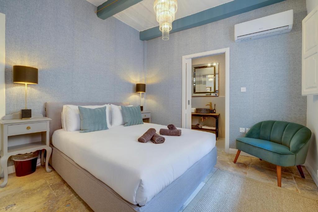 森格萊阿的住宿－Charming Maltese Townhouse in Senglea，卧室配有一张白色大床和一张绿色椅子