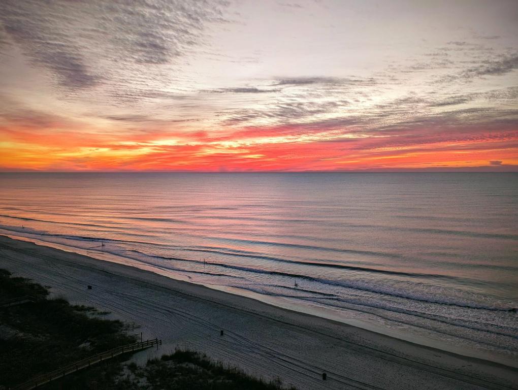 a sunset over the ocean with people walking on the beach at Oceanfront Get Away in Myrtle Beach