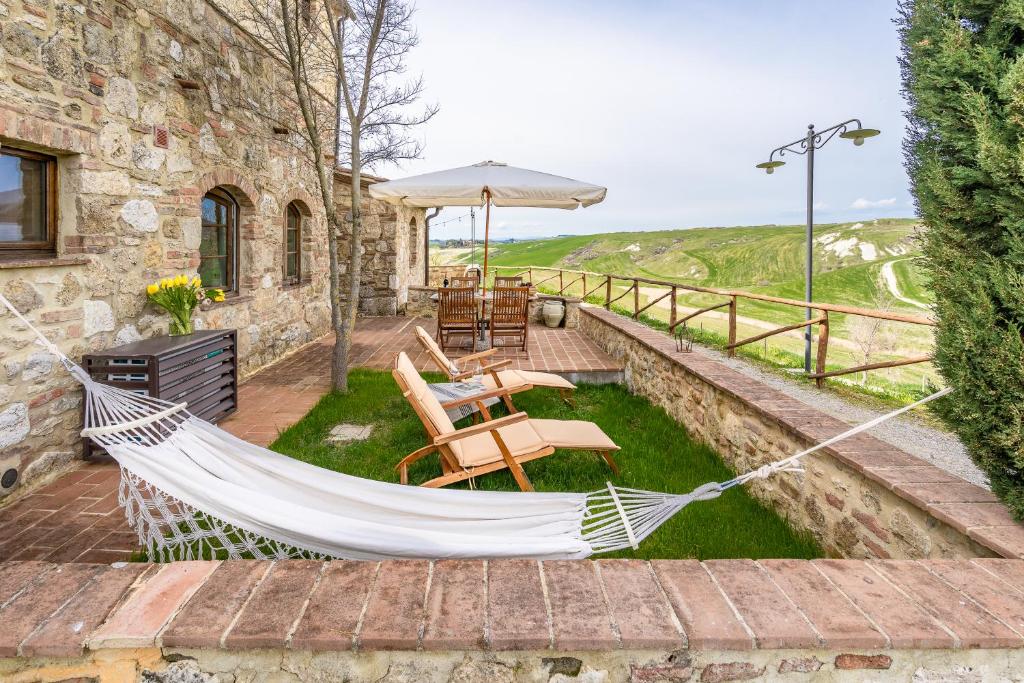 a hammock on the patio of a stone house at Il Cipresso del Fossaccio in Asciano