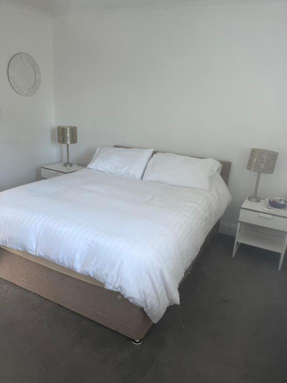 een slaapkamer met een wit bed en 2 nachtkastjes bij Mayfield guest rooms in Bromley