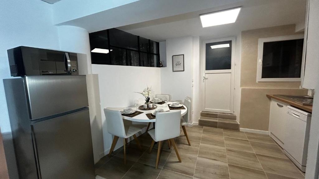 a kitchen with a table with chairs and a refrigerator at PRIMO - Logement 4/6 personnes in Braux