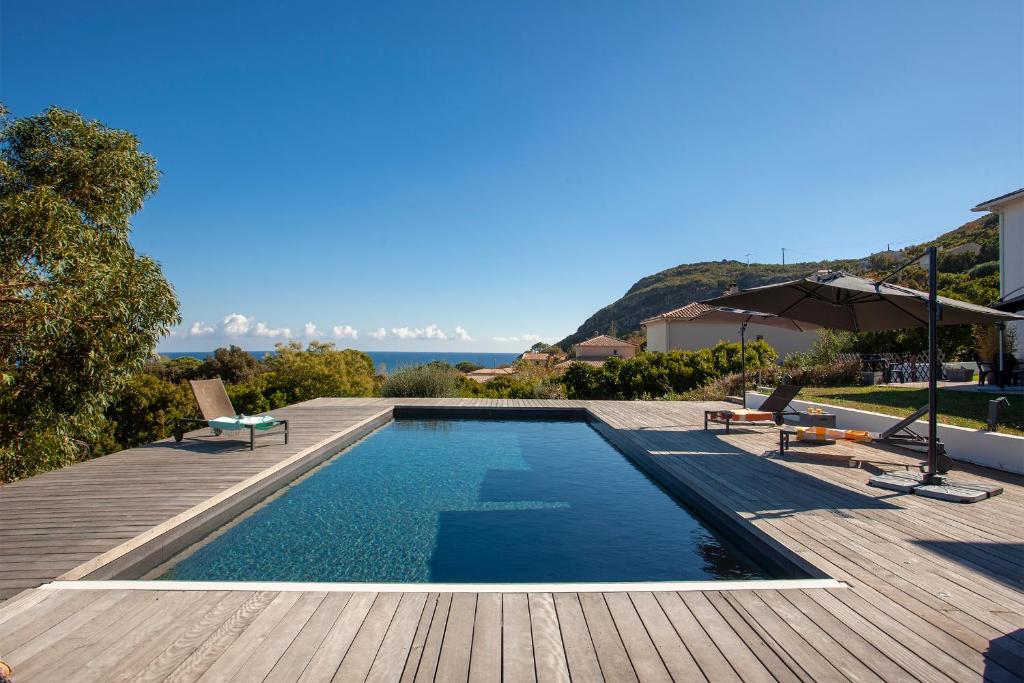 a swimming pool on a wooden deck next to a house at VILLA KIM SISCU a 300m de la plage in Sisco