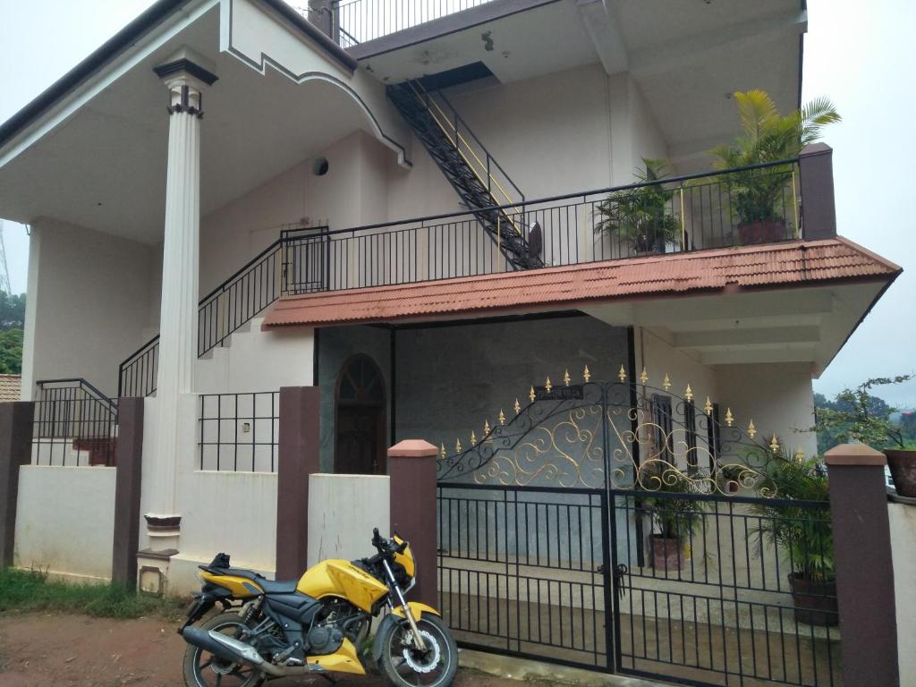 Coorg villas apartment stay في ماديكيري: دراجة نارية صفراء متوقفة أمام مبنى
