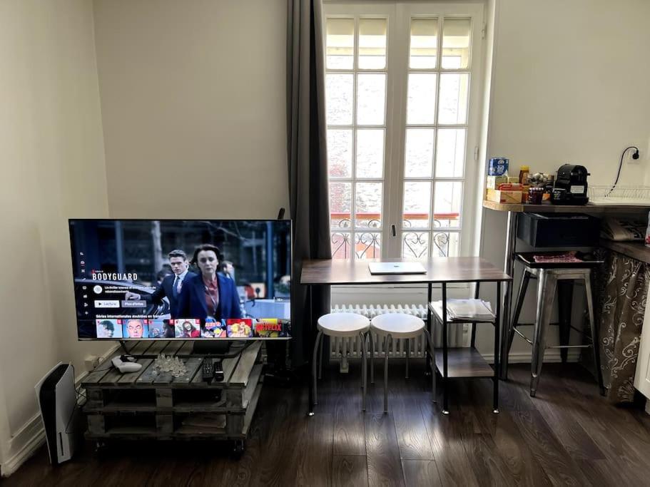 sala de estar con TV y mesa en Le Petit Nid Urbain, en Levallois-Perret