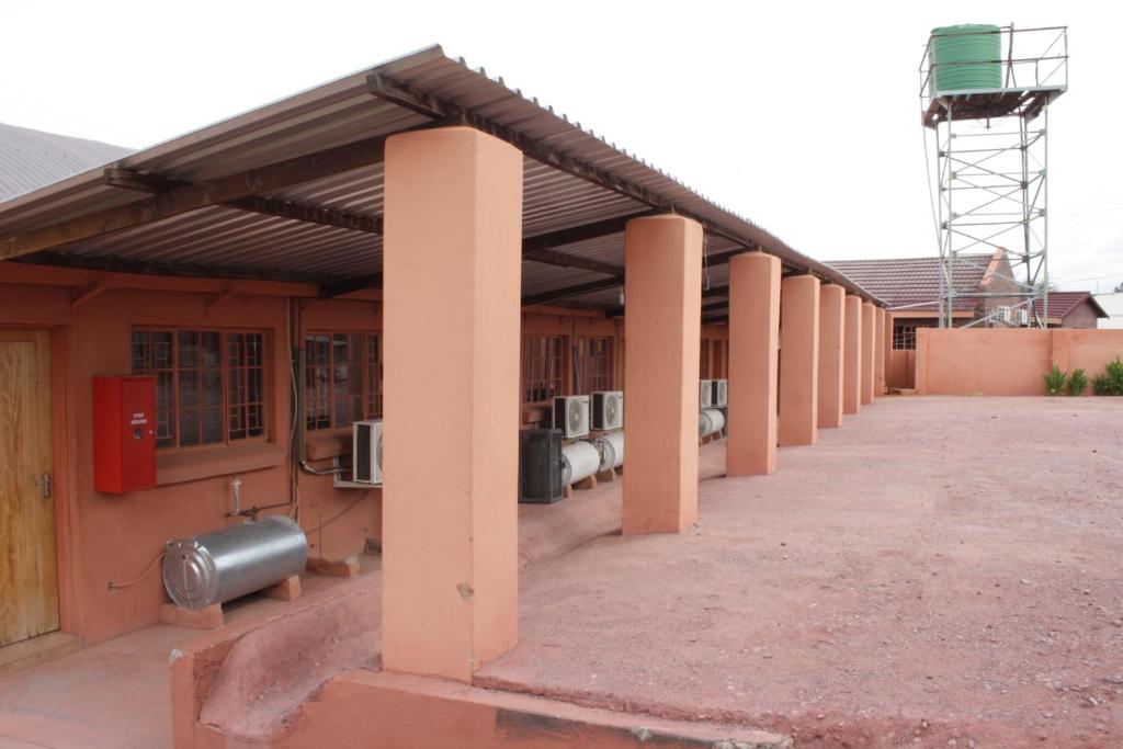a building with a row of columns and tanks on it at Rheotessa Deben in Dagbreek