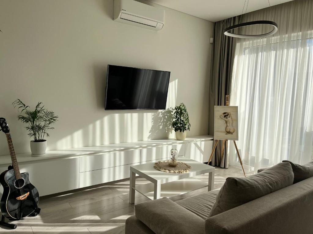 ein Wohnzimmer mit einem Sofa, einem Tisch und einer Gitarre in der Unterkunft Cozy Apartment with Garden & Terrace in Kaunas in Kaunas