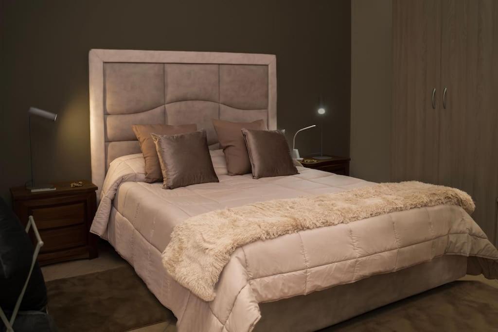 a bedroom with a large bed with a large headboard at Le Cento Sculture Apartment in Belpasso