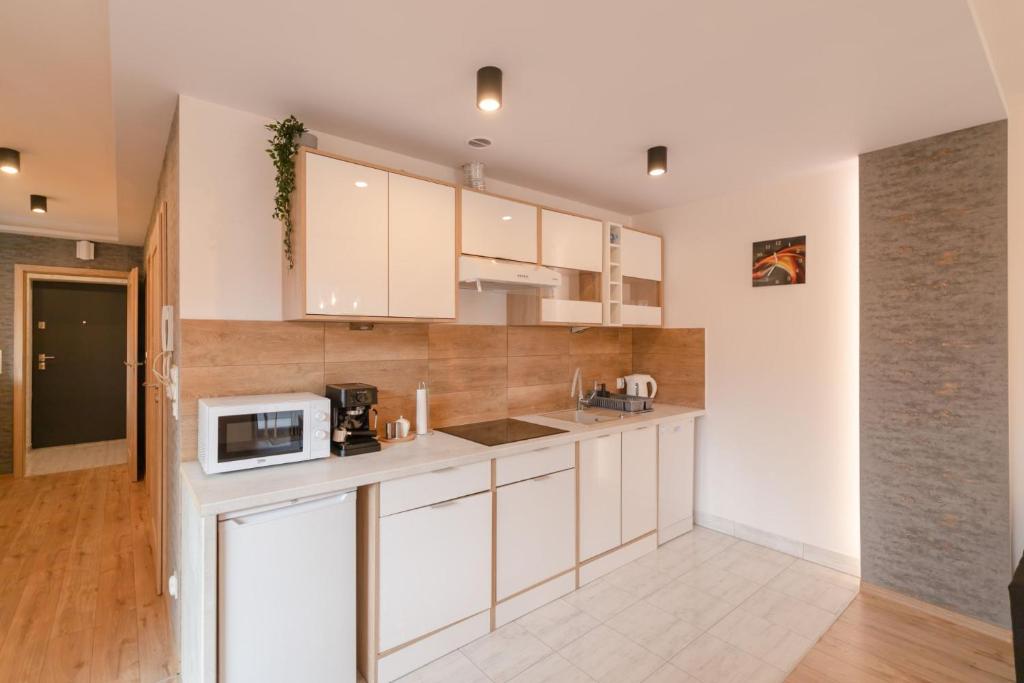 a kitchen with white cabinets and a microwave at ApartView Plażowa Residence with parking by Rent like home in Szczyrk