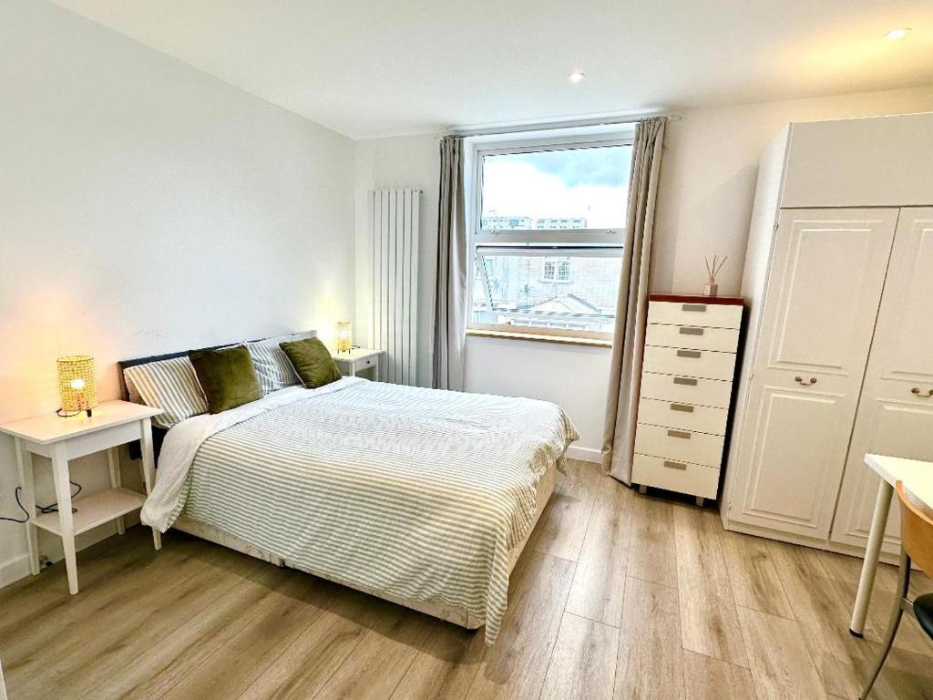 Schlafzimmer mit einem Bett, einem Schreibtisch und einem Fenster in der Unterkunft Large En-Suite Studio with private bath and kitchen In Canary Wharf 4 in London