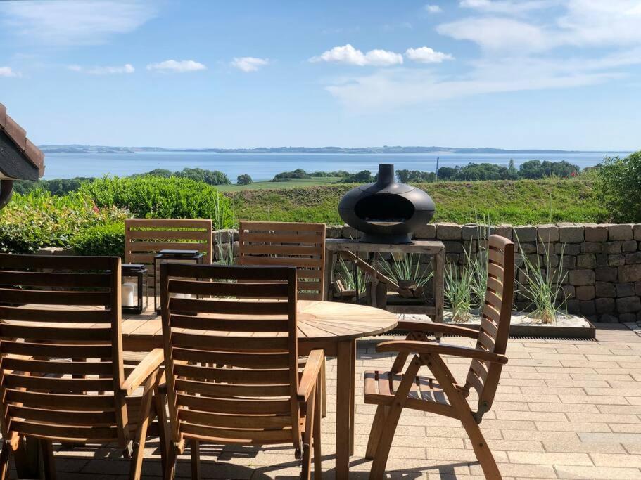a table and two chairs and a grill on a patio at Luxury house with breathtaking sea view of Mols in Rønde