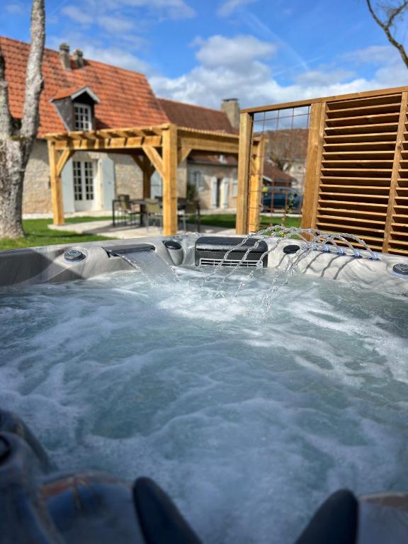 un bain à remous avec de l'eau dans une arrière-cour avec une maison dans l'établissement Gîte avec jacuzzi 6 personnes, à Brouchaud
