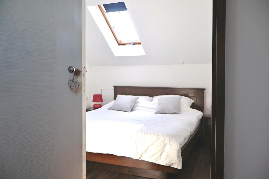 a bedroom with a bed with white sheets and a skylight at Sarajevo Sky Suite in Sarajevo