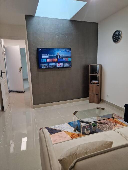 un salon avec un canapé et une télévision sur un mur dans l'établissement F2 type apartment Near Stade de France, à Saint-Denis