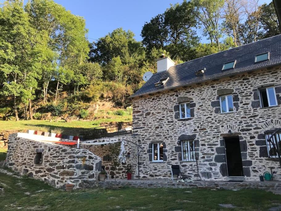 een oud stenen huis met een zwart dak bij Les Termes in Saint-Chély-dʼAubrac