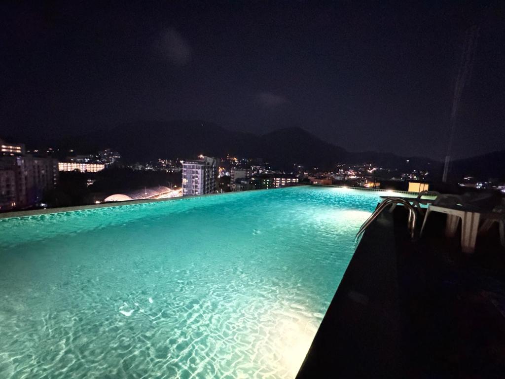 een groot zwembad 's nachts met een stad bij Zephyr Grand Hotel in Patong Beach