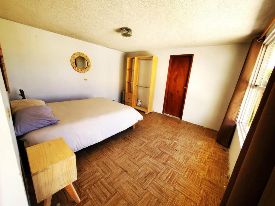 een slaapkamer met een bed en een houten vloer bij JocoHideaway in Jocotitlán