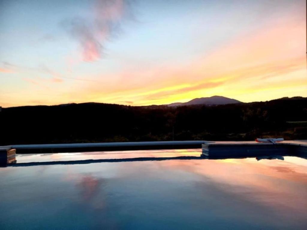 - une vue sur la piscine et le coucher de soleil en arrière-plan dans l'établissement Villa privative des cinq tours avec piscine, à Vinezac