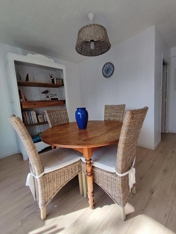 une table en bois avec des chaises en osier et un vase bleu. dans l'établissement T2 jardin privatif et accès piscine, à Ploeren