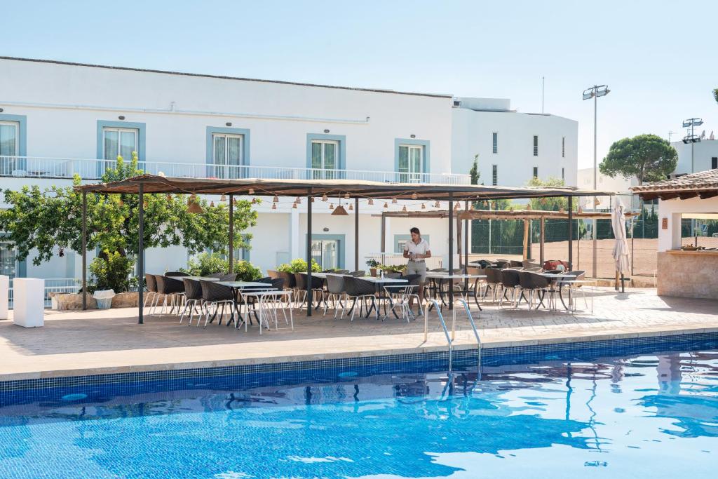 a man sitting at a table next to a swimming pool at Villa Real Club Apartments in Camp de Mar