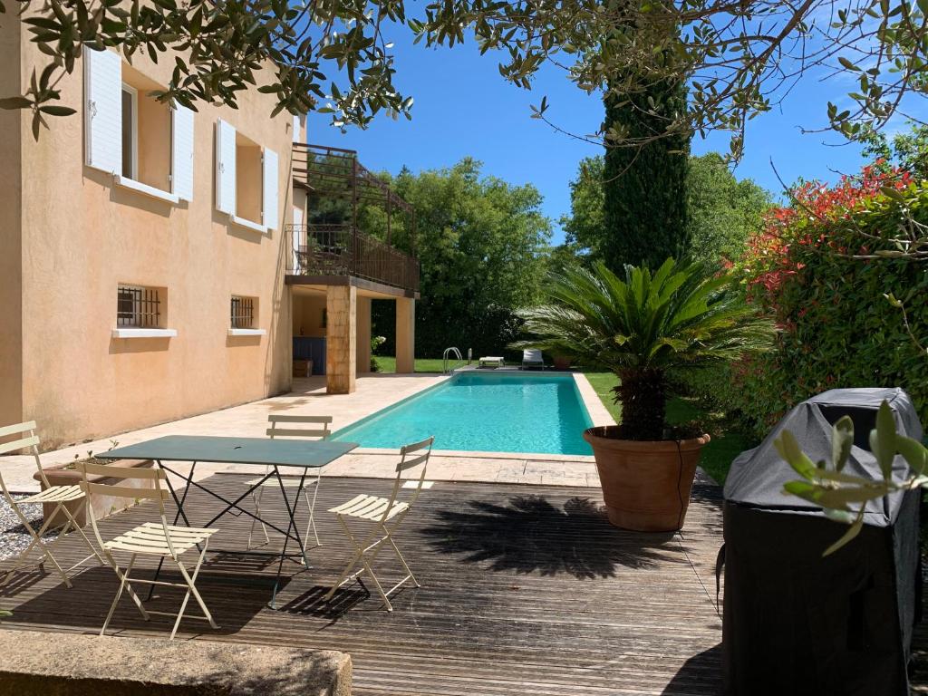 einen Pool mit einem Tisch und Stühlen neben einem Gebäude in der Unterkunft la grande villa in Aix-en-Provence