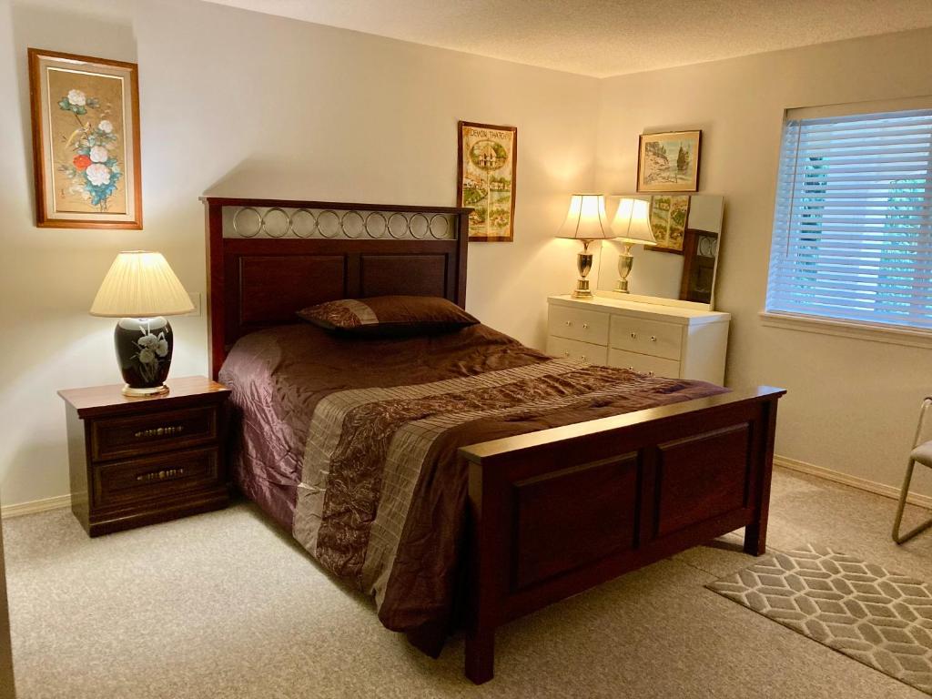 a bedroom with a bed and a lamp and a window at Red Robe B&B in Nanaimo