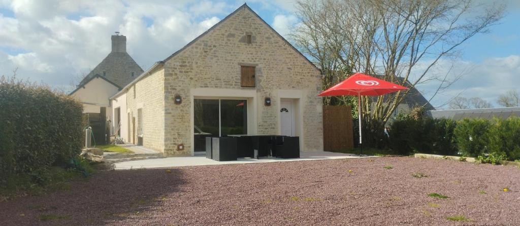 a house with a red umbrella in front of it at Gite de la longue fosse in Mandeville-en-Bessin