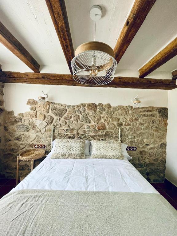 a bedroom with a bed with a stone wall at El Capricho de la Serranía II in Tragacete